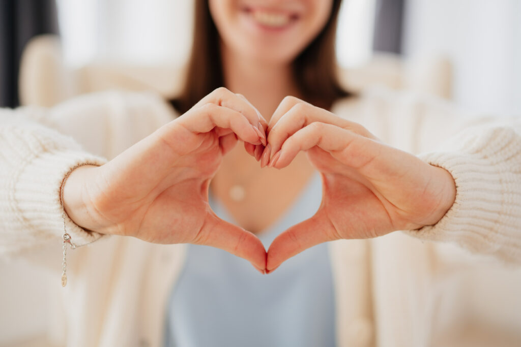 Žena tvoří rukama srdíčko jako symbol touhy po miminku a sledování bazální teploty.