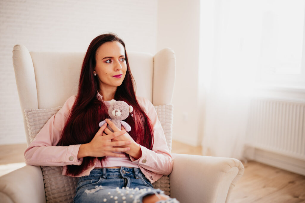 Žena držící v ruce medvídka přemýšlí o miminku.